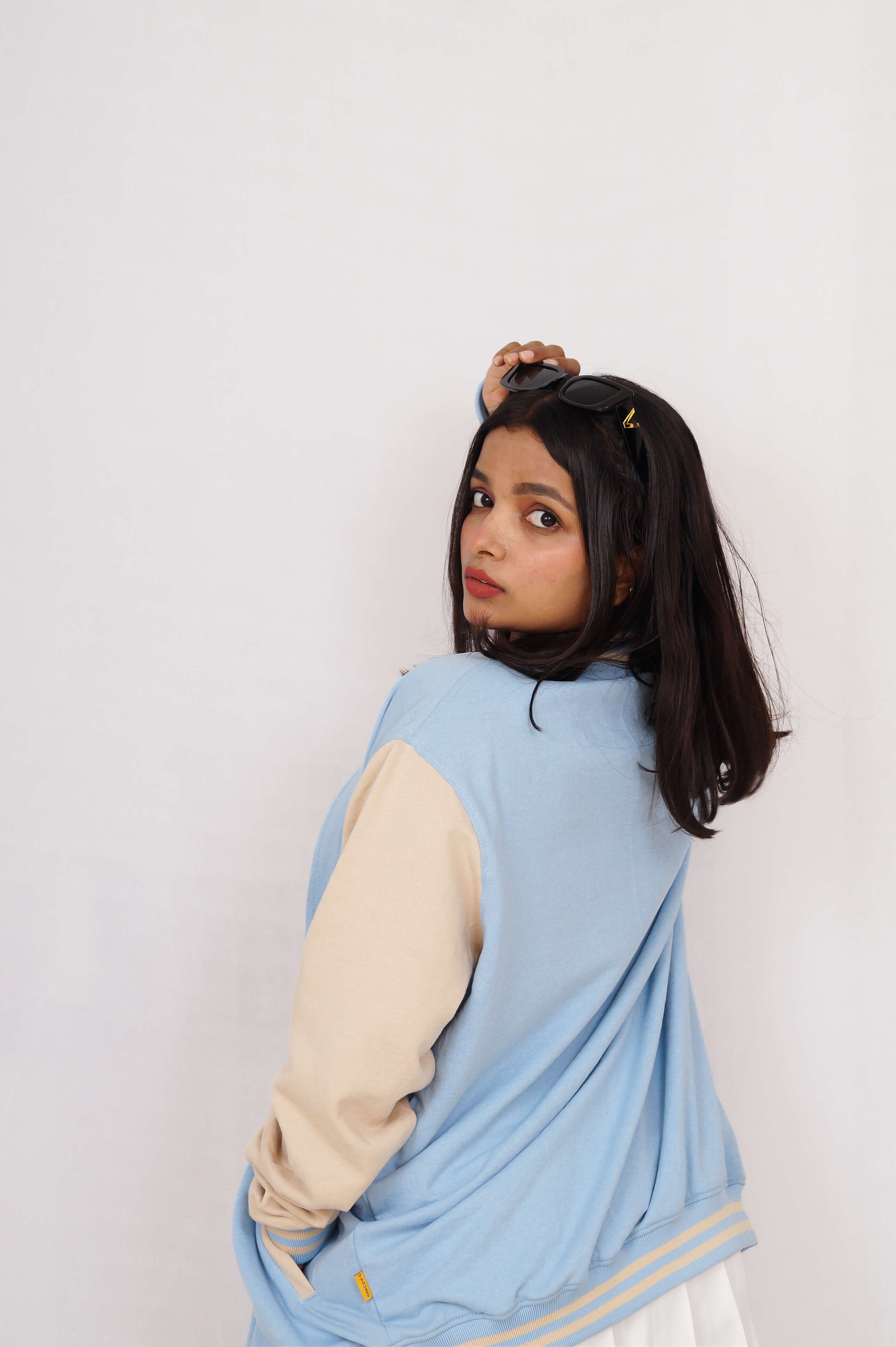 Person wearing a light blue cardigan over a beige long-sleeve shirt on a white background
