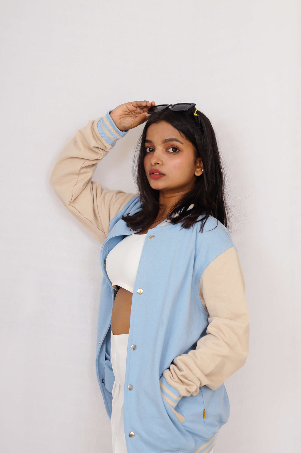 Woman wearing a light blue and beige jacket against a white background