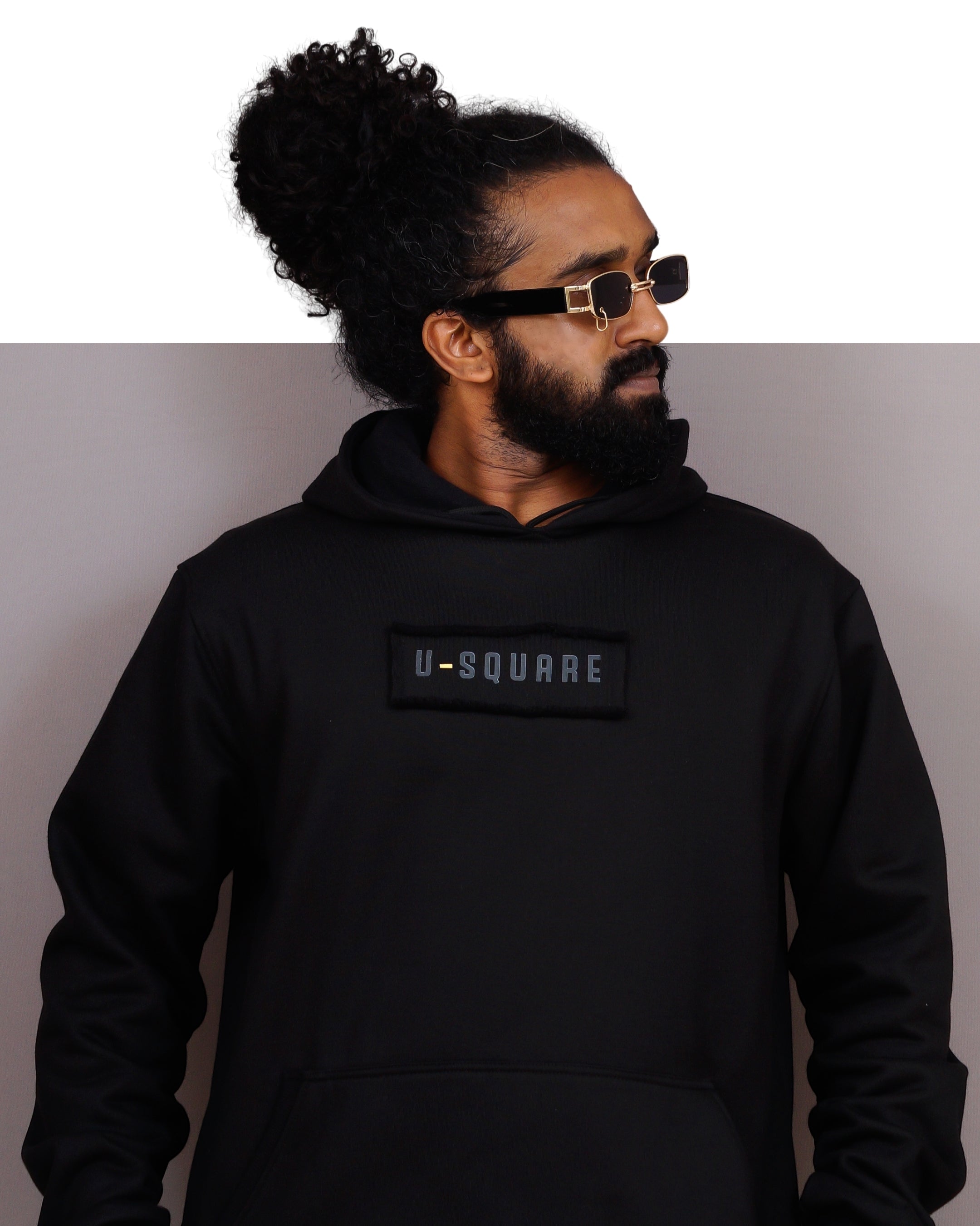 Person wearing a black hoodie with 'U-Square' logo on a plain background