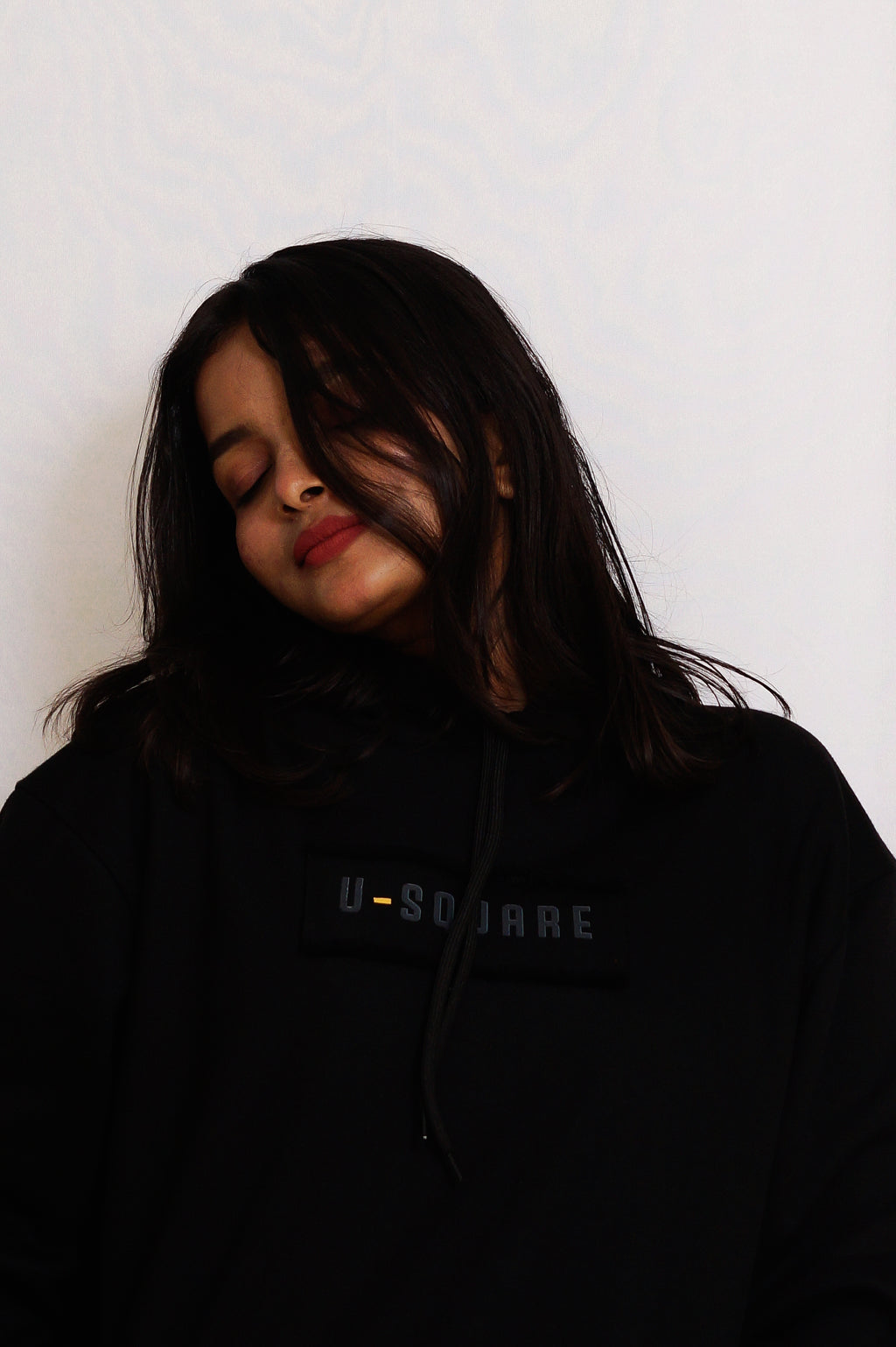 Person wearing a black hoodie with 'U-Square' branding against a white background