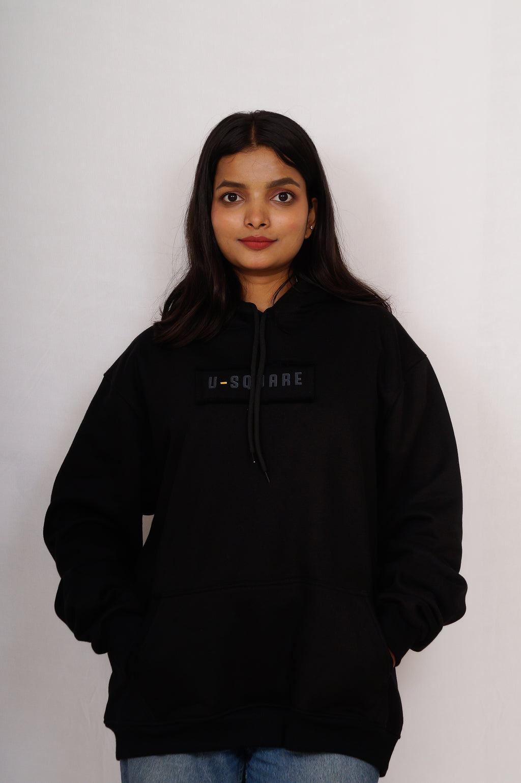 Person wearing a black hoodie with a brand logo on a white background