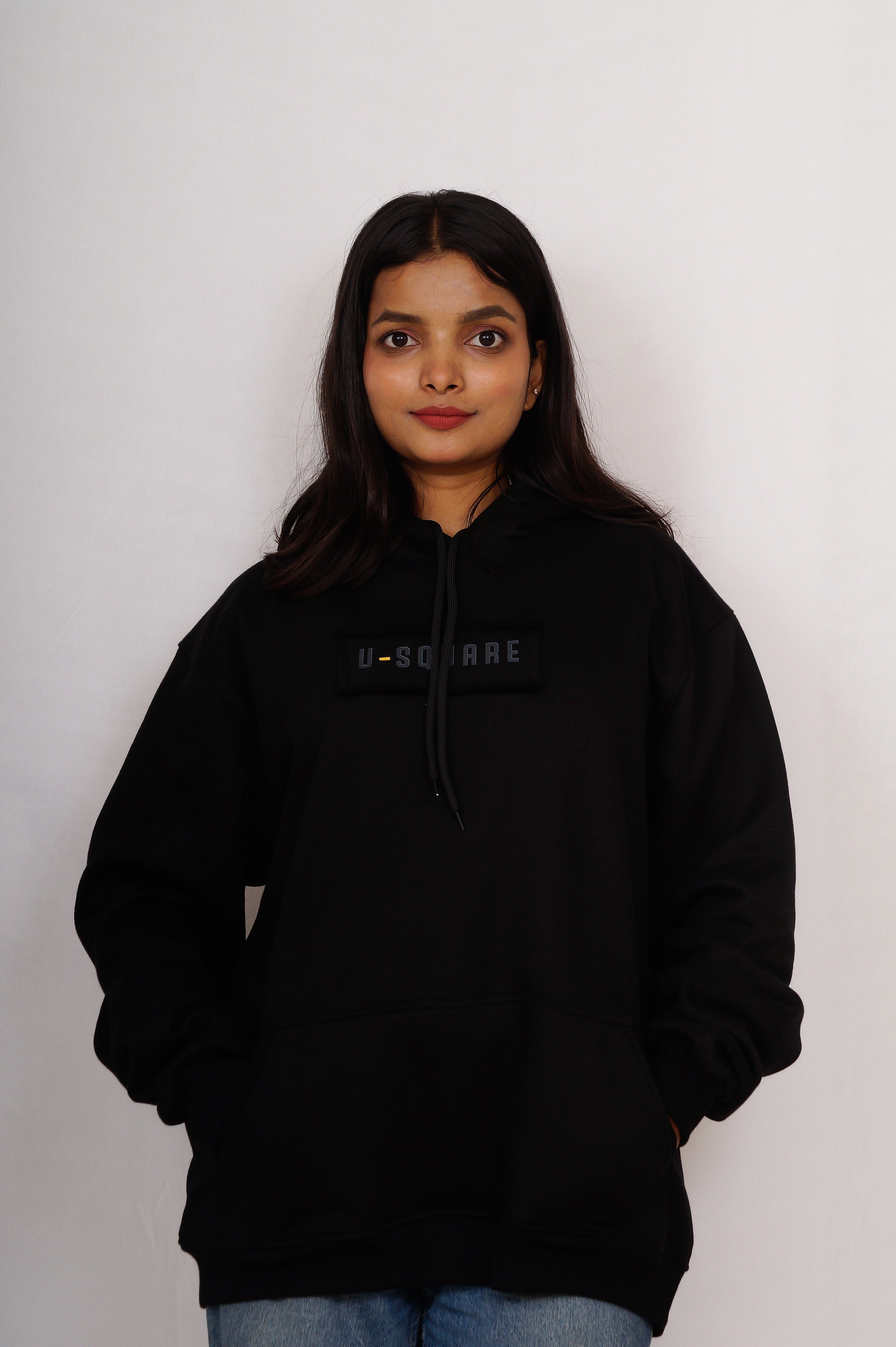Person wearing a black hoodie with a brand logo on a white background