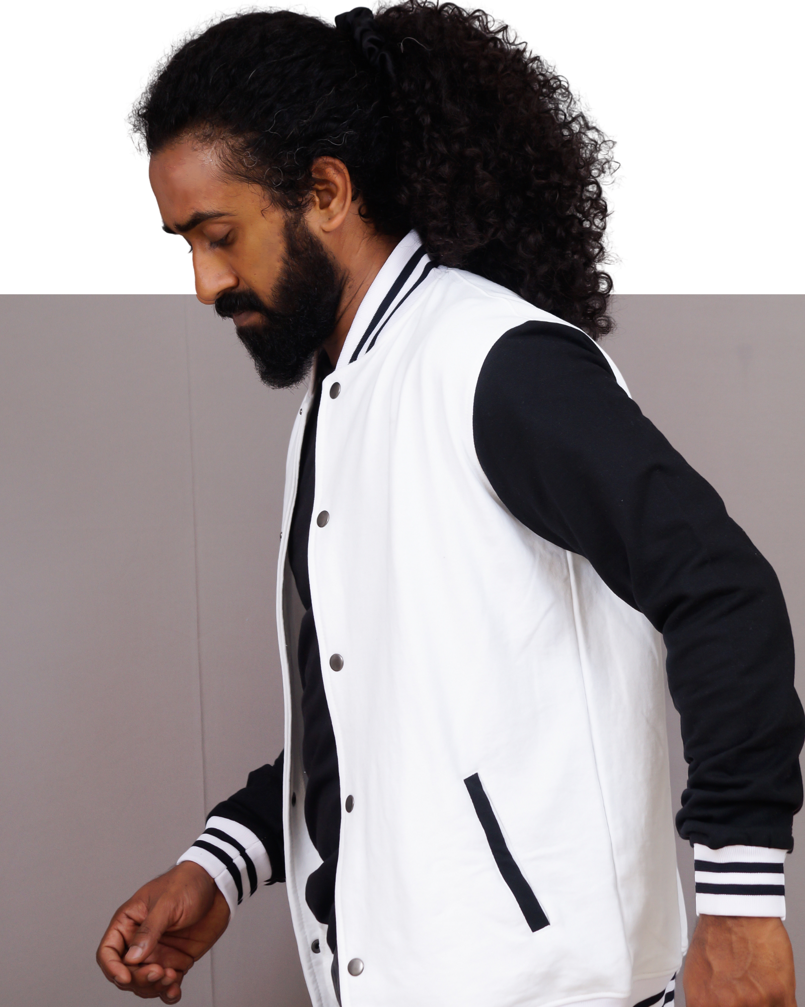 Man wearing a white and black varsity jacket against a plain background
