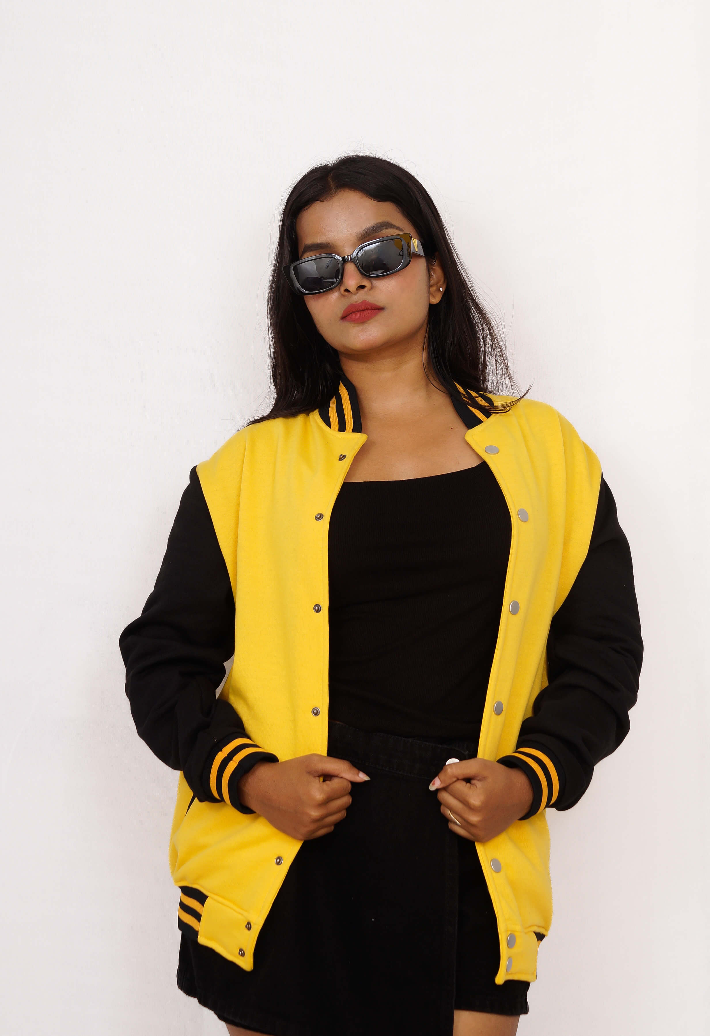 Person wearing a black and yellow varsity jacket on a white background