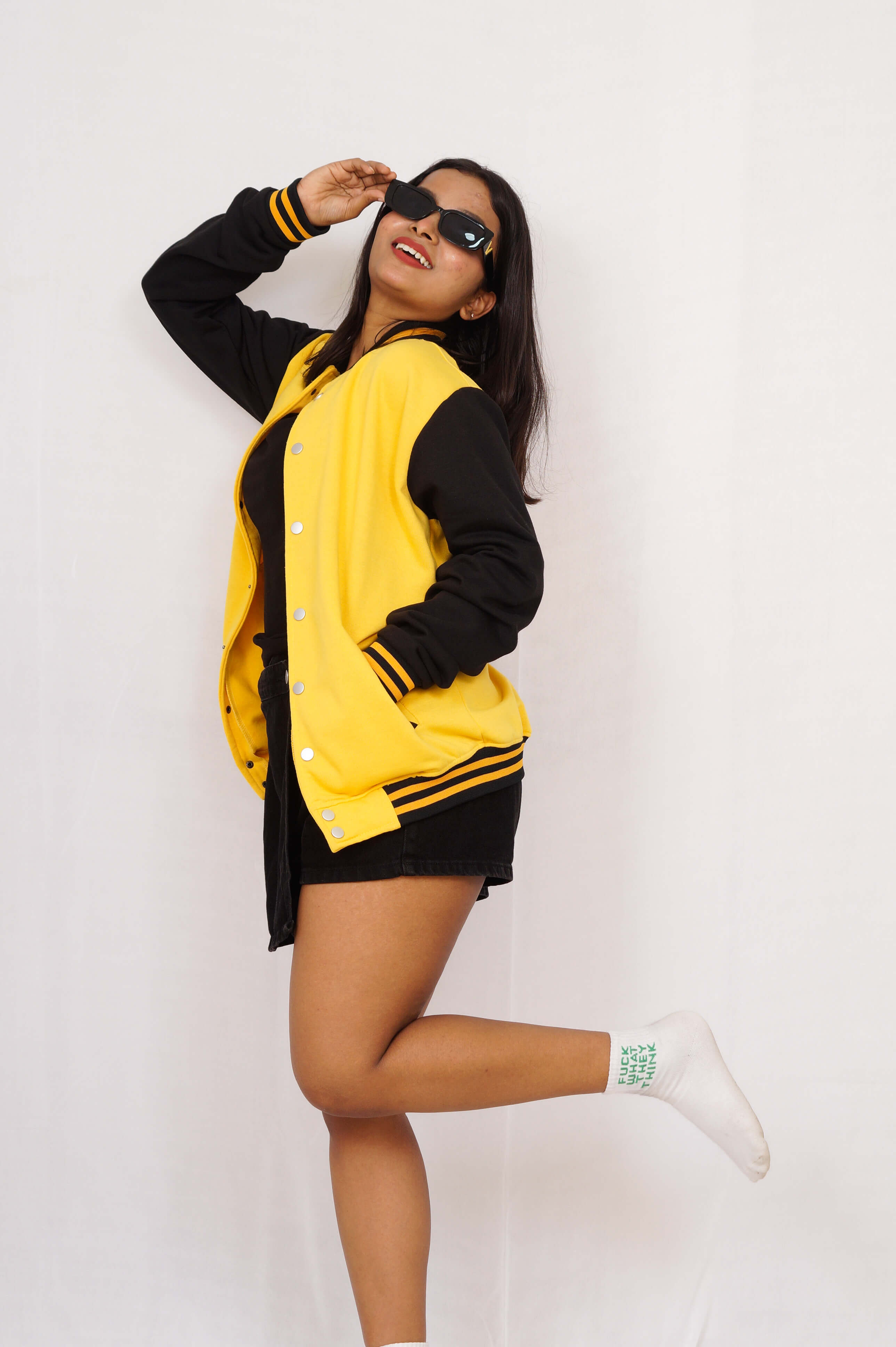Person wearing a yellow and black varsity jacket on a white background