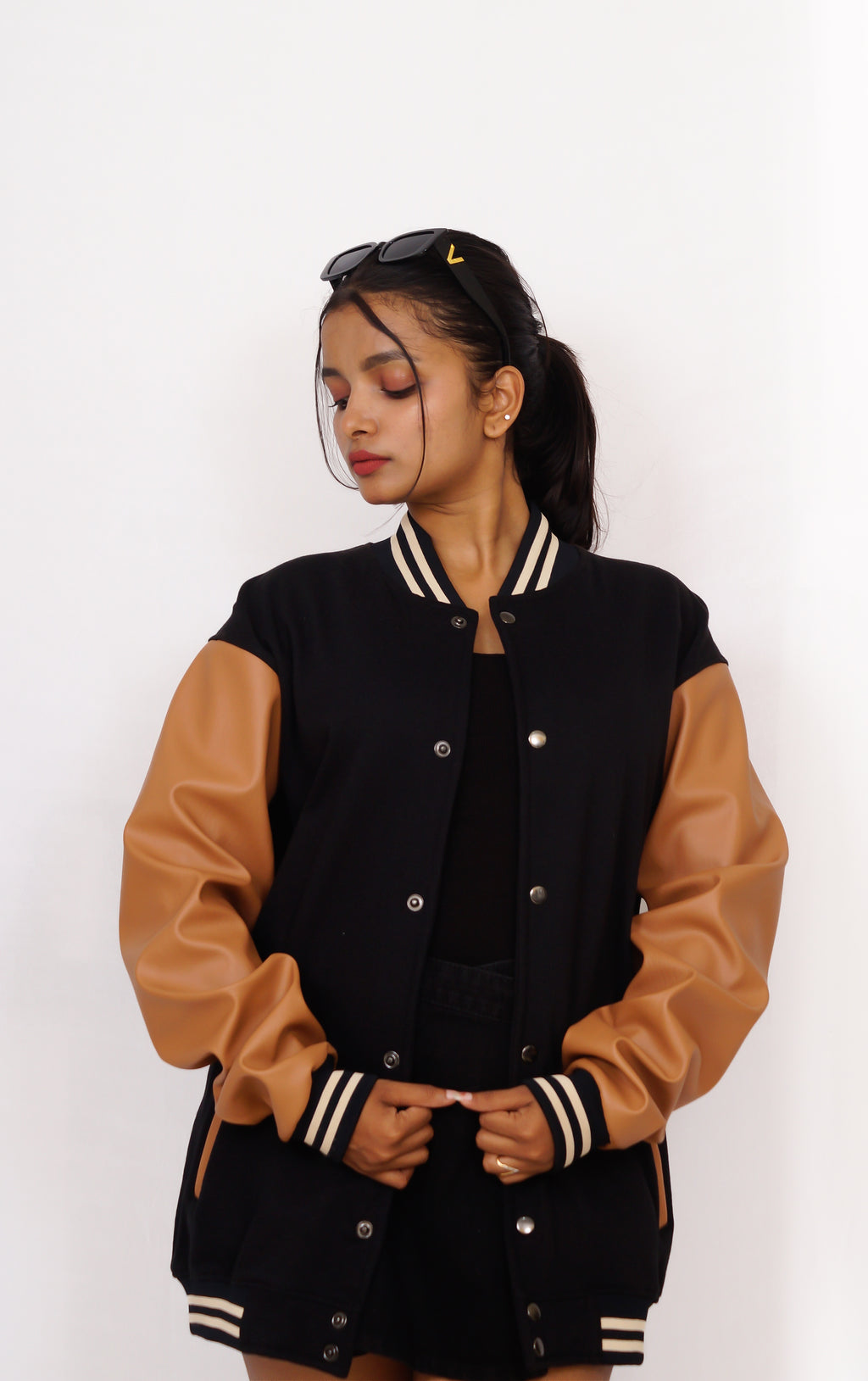 Person wearing a black and brown varsity jacket on a white background
