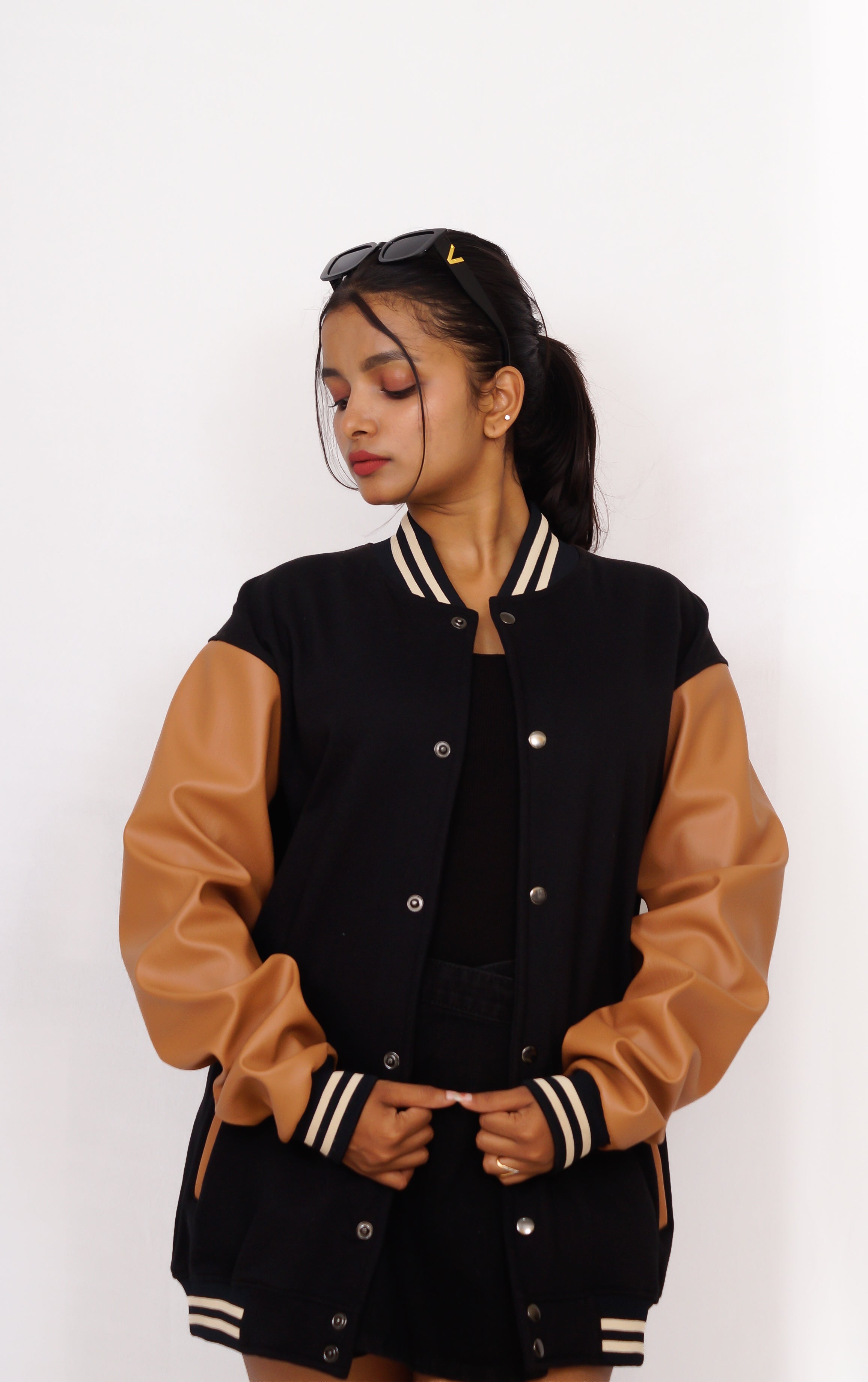 Person wearing a black and brown varsity jacket on a white background
