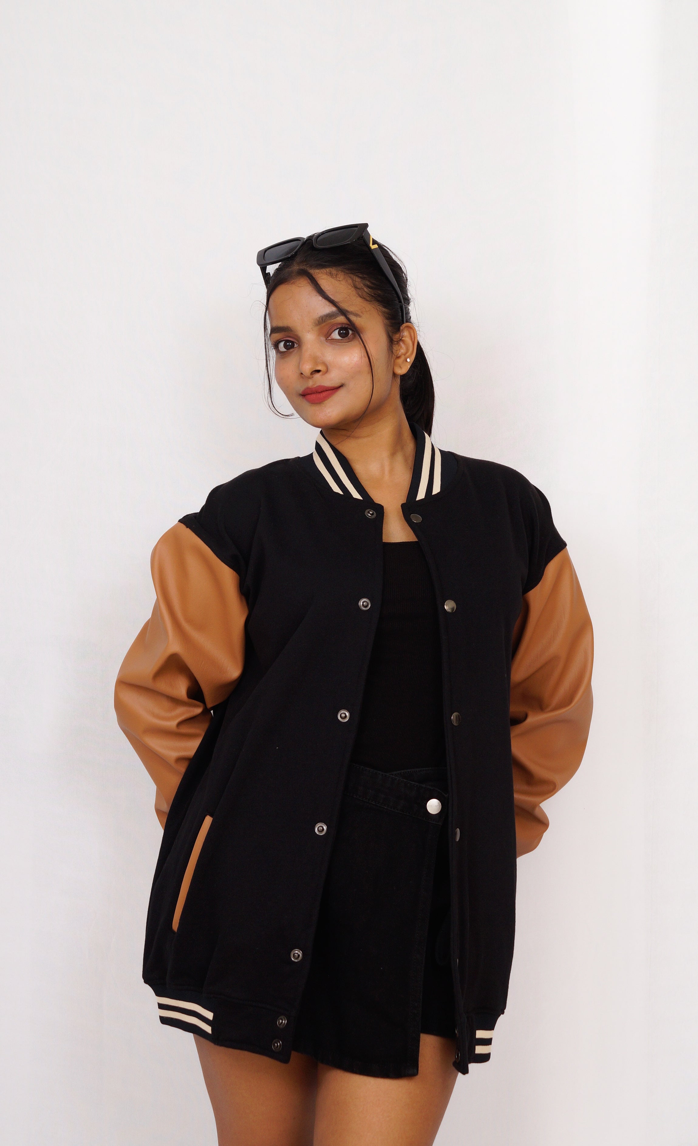 Woman wearing a black and brown varsity jacket on a white background