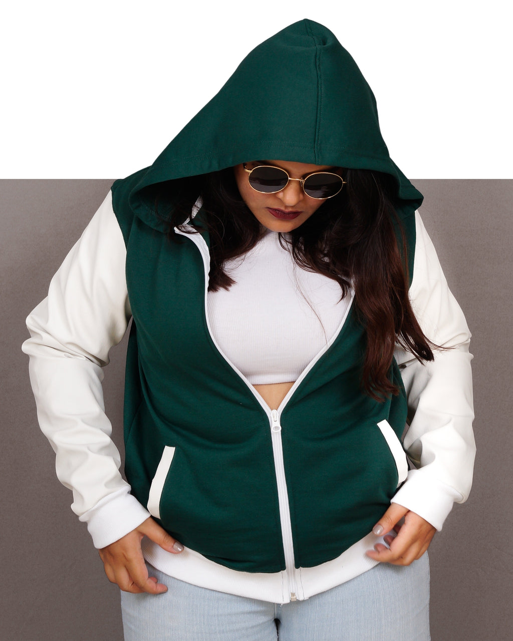 Person wearing a green and white hoodie with sunglasses on a gray background
