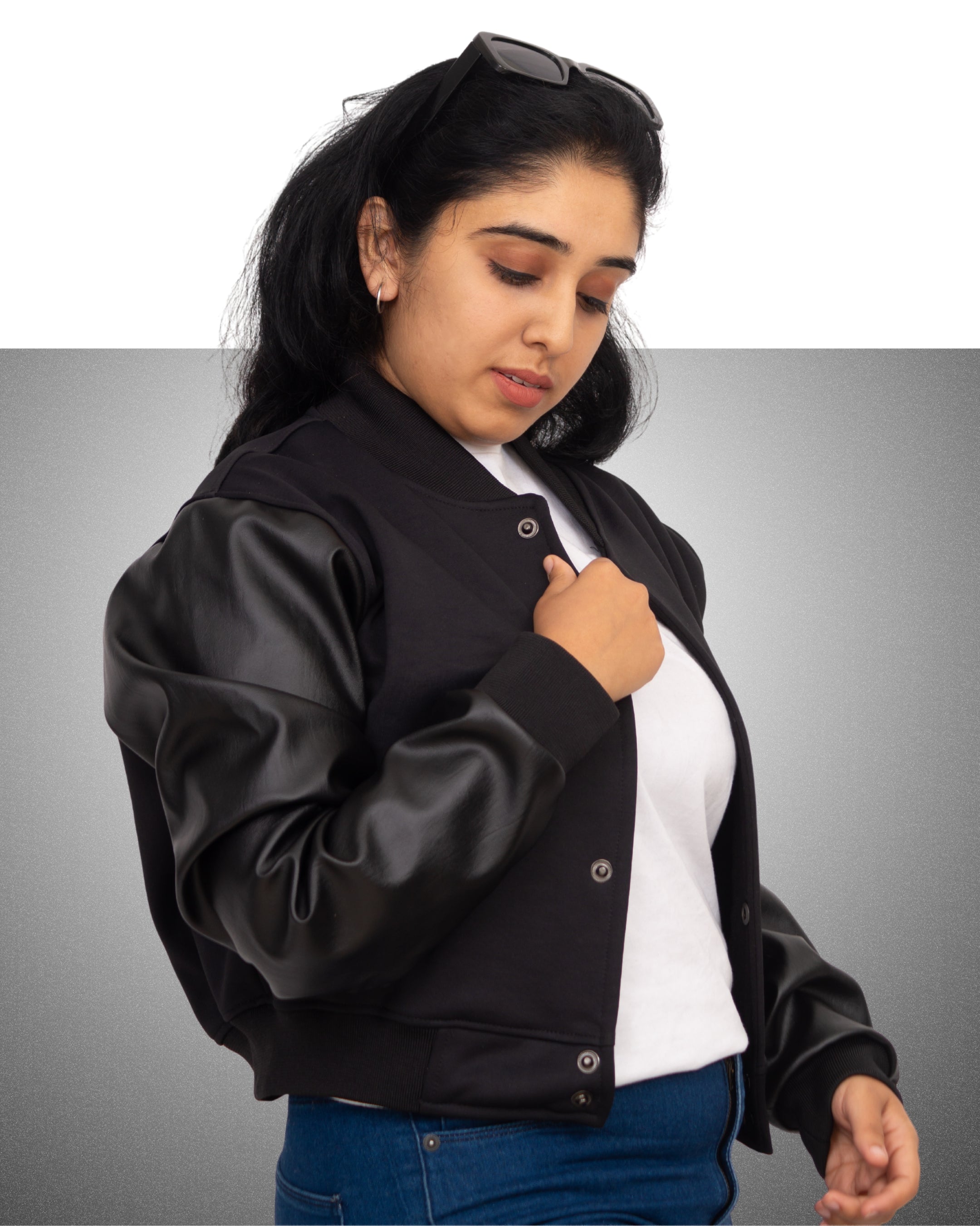 Woman wearing a black leather jacket over a white shirt on a gray background