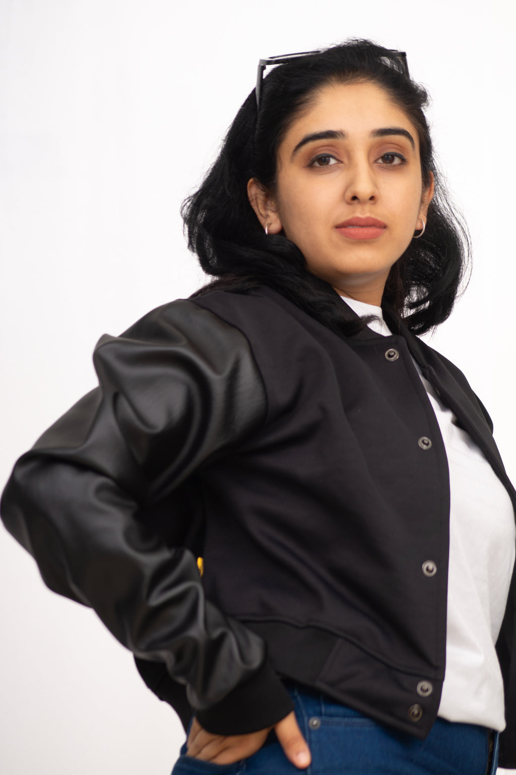 Woman wearing a black bomber jacket over a white shirt on a white background