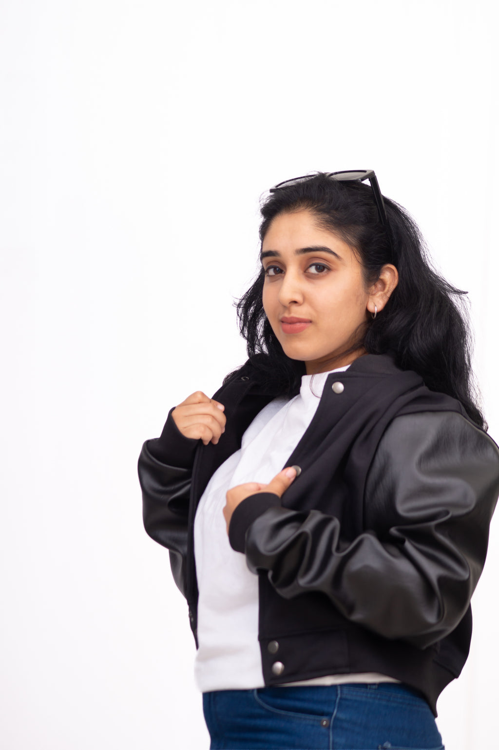 Woman wearing a black and gray varsity jacket on a white background