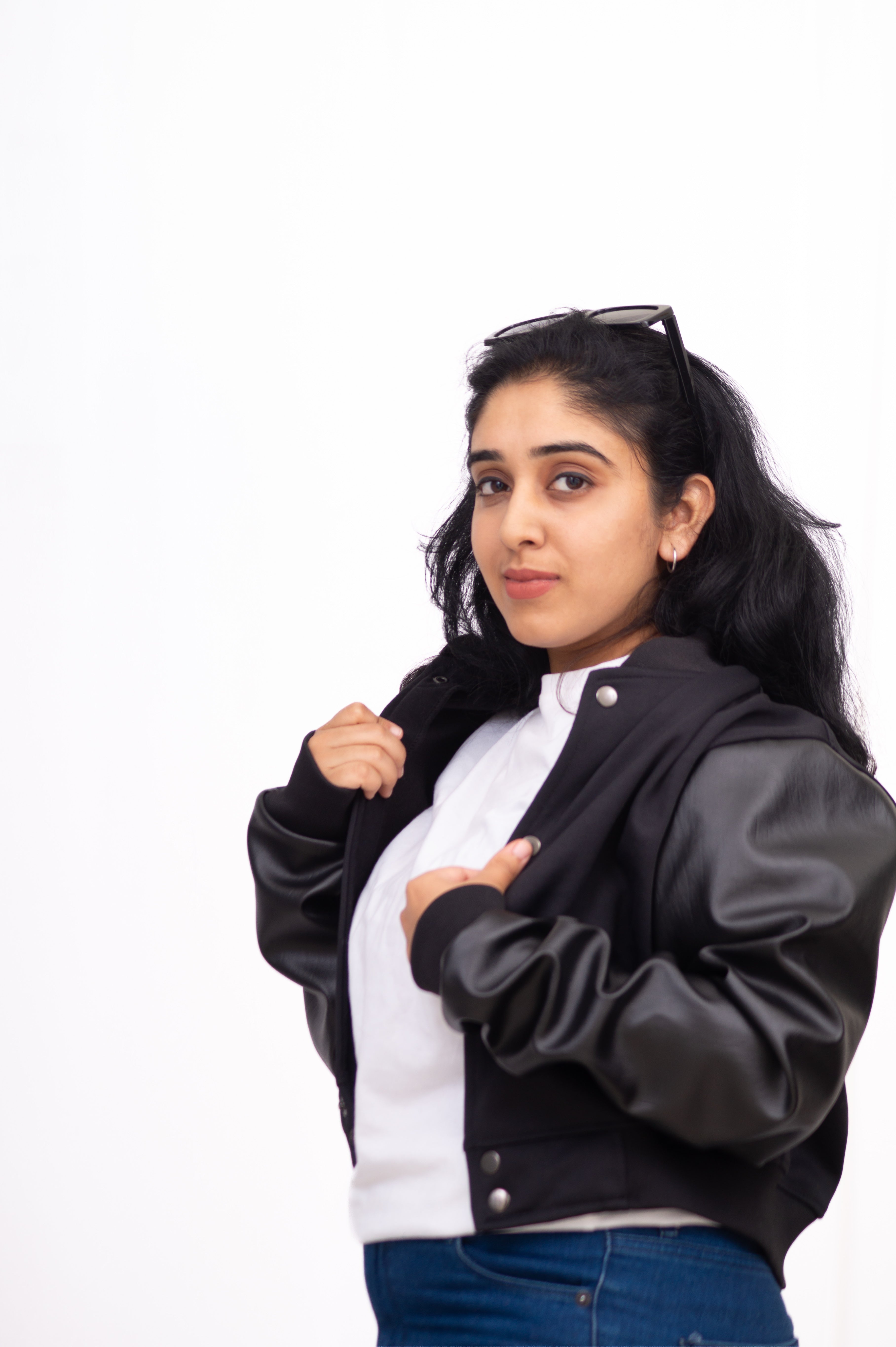 Woman wearing a black and gray varsity jacket on a white background