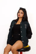 Woman wearing a black varsity jacket with a letter 'I' on a white background