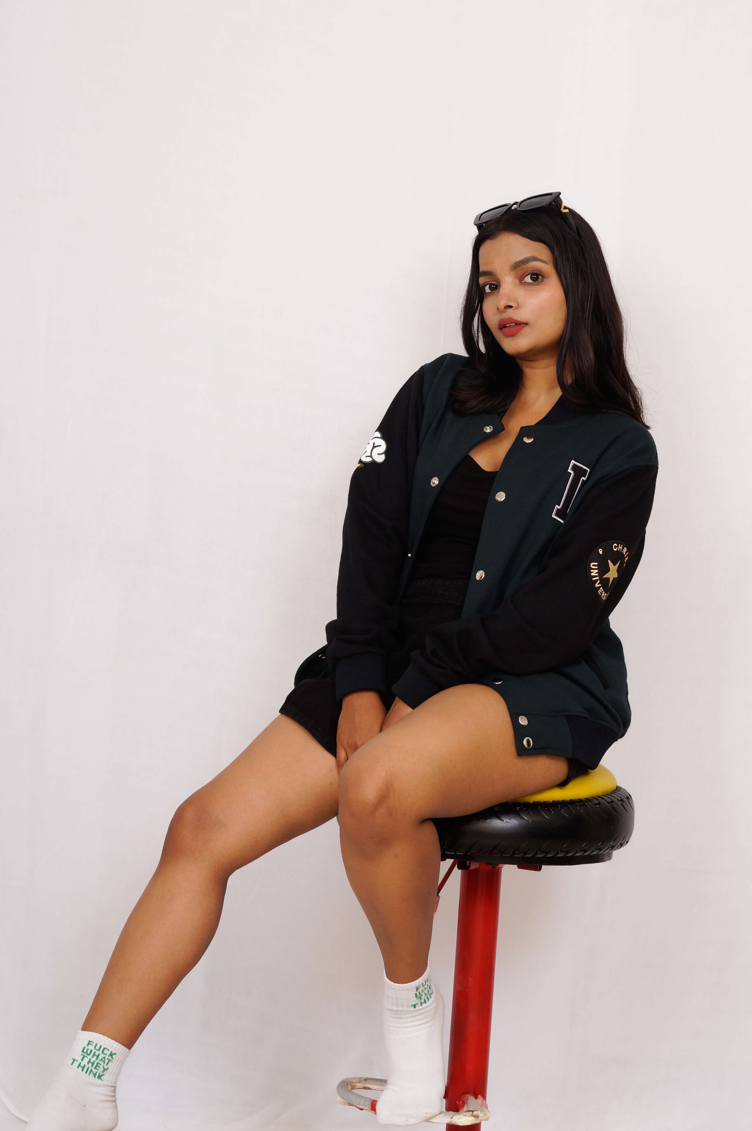 Woman sitting on a red stool against a white background
