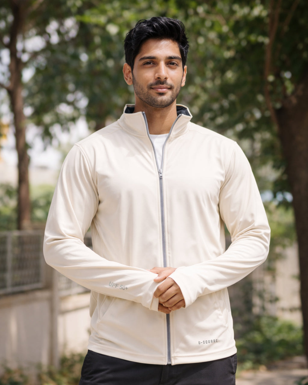 Man wearing a white jacket outdoors with trees in the background