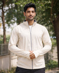 Man wearing a white jacket outdoors with trees in the background
